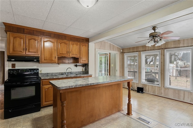 kitchen featuring sink, wood walls, a center island, black range with electric cooktop, and ceiling fan