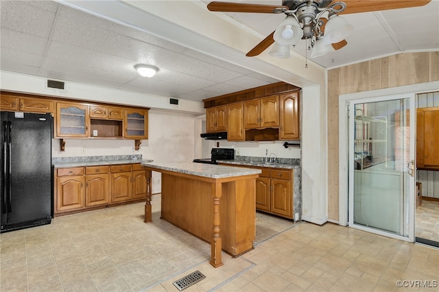 kitchen with sink, black appliances, a kitchen breakfast bar, a kitchen island, and a drop ceiling