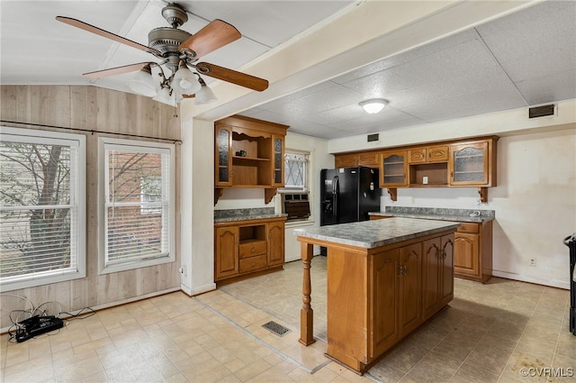 kitchen featuring dishwasher, a kitchen breakfast bar, a kitchen island, black fridge with ice dispenser, and vaulted ceiling