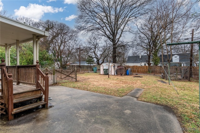 view of yard featuring a wooden deck, a storage unit, and a patio