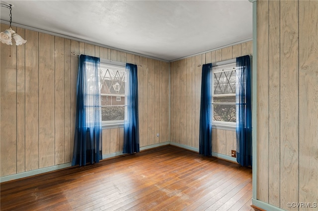 unfurnished room featuring hardwood / wood-style floors, plenty of natural light, and wooden walls