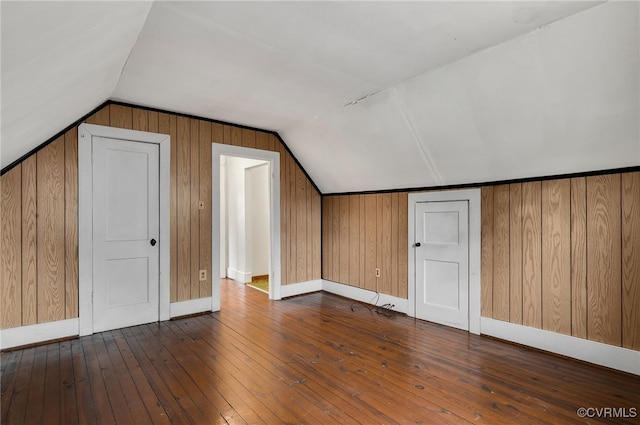 additional living space featuring hardwood / wood-style flooring, vaulted ceiling, and wooden walls