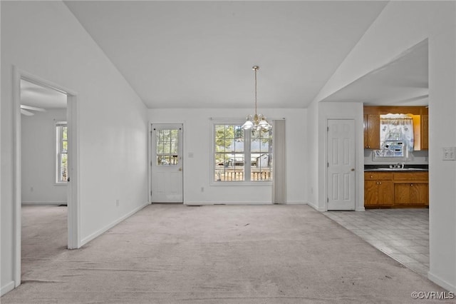 unfurnished dining area with lofted ceiling, sink, light colored carpet, and a chandelier