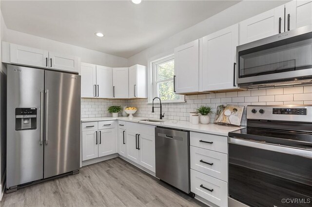 kitchen featuring appliances with stainless steel finishes, decorative backsplash, white cabinetry, and sink