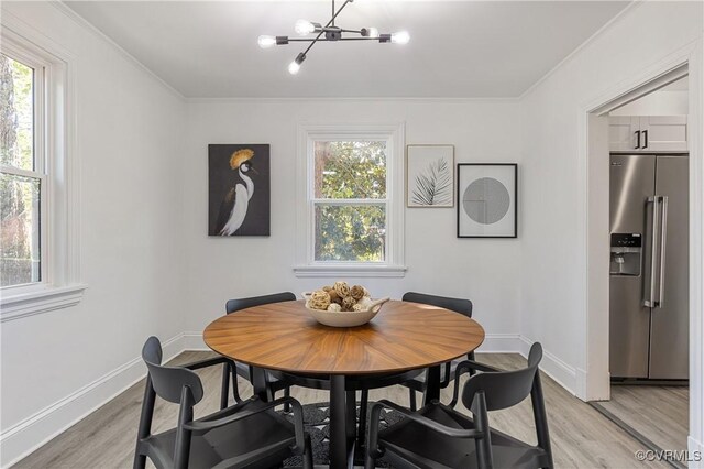 dining room with a notable chandelier, ornamental molding, and light hardwood / wood-style flooring