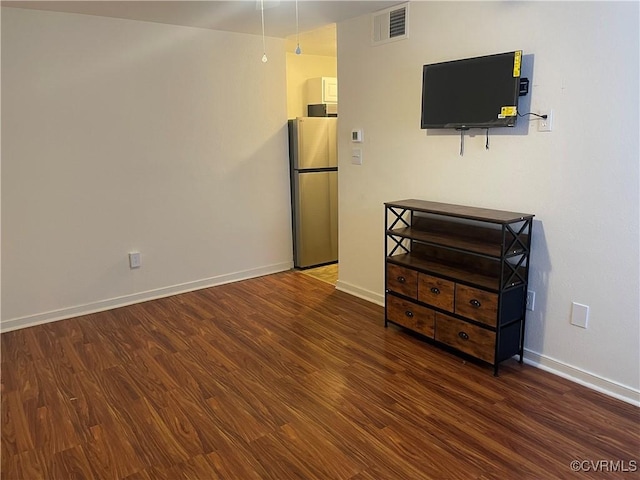 bedroom with dark wood-type flooring and stainless steel fridge