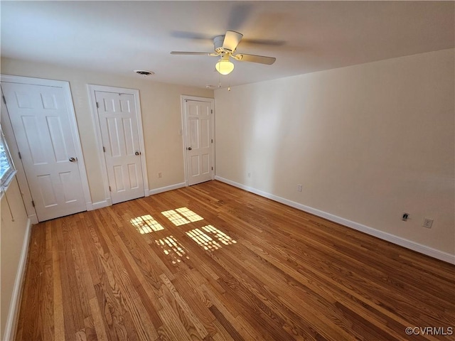 unfurnished bedroom with ceiling fan, light hardwood / wood-style flooring, and multiple closets