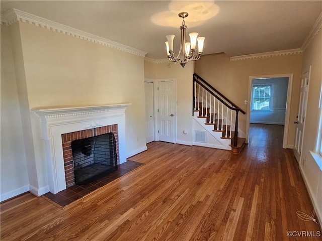 unfurnished living room with dark wood-type flooring, a fireplace, crown molding, and a notable chandelier