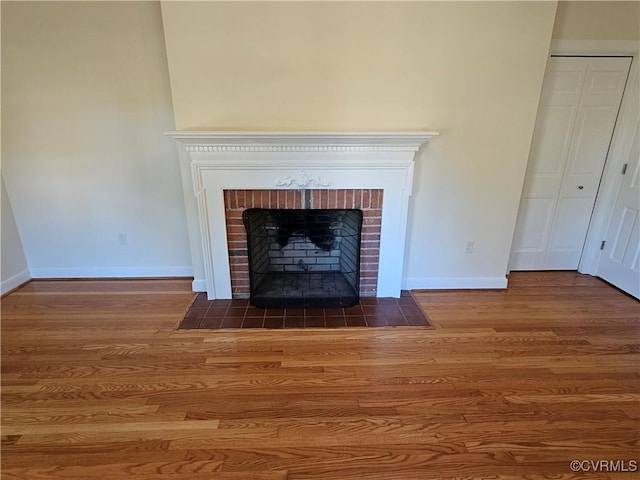 interior details featuring hardwood / wood-style flooring and a brick fireplace