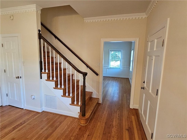 foyer entrance featuring wood-type flooring and crown molding