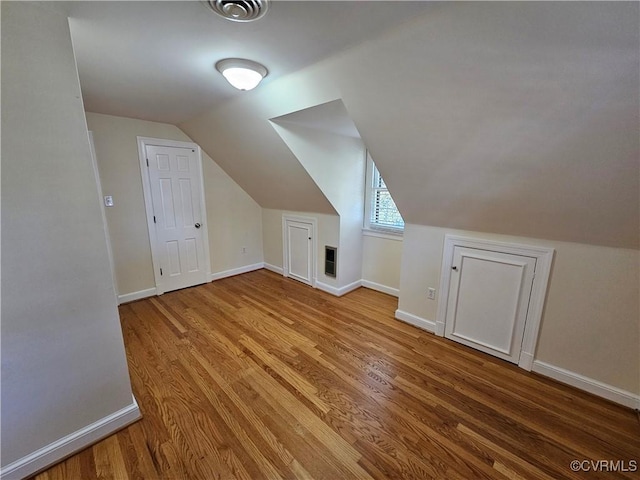 bonus room with light wood-type flooring and vaulted ceiling