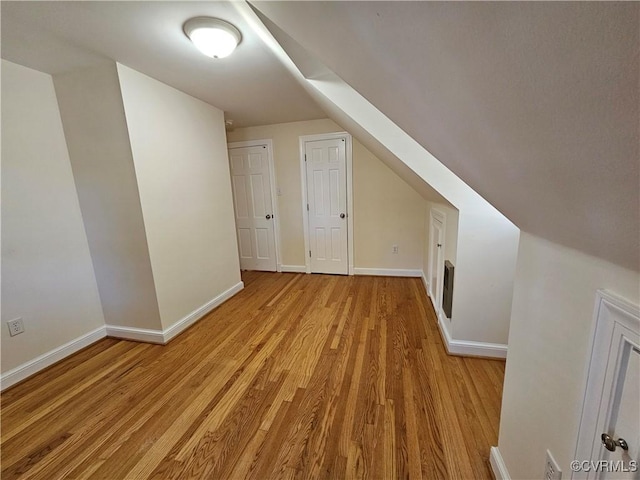 additional living space featuring vaulted ceiling and light hardwood / wood-style floors