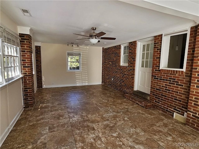 unfurnished living room featuring ceiling fan and brick wall