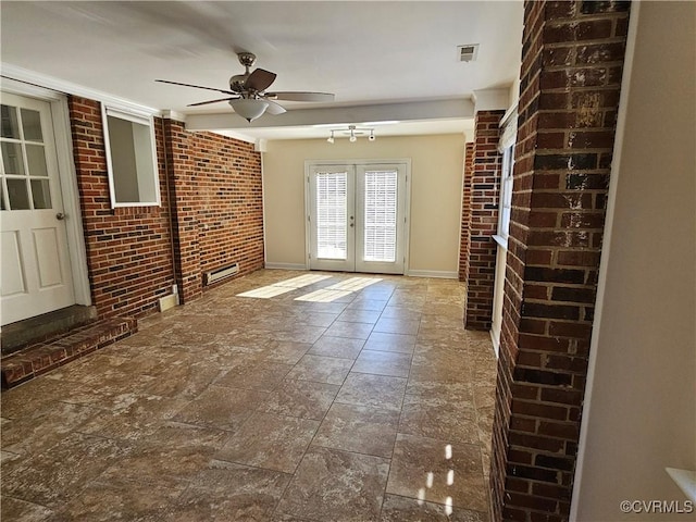 interior space with ceiling fan, french doors, and brick wall