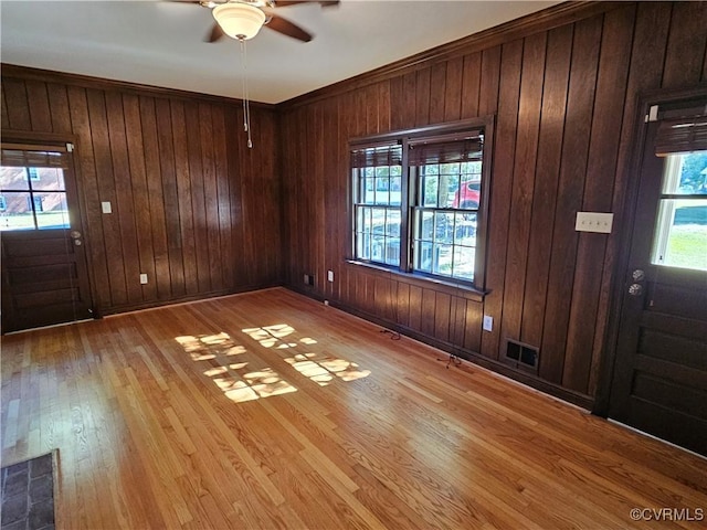 entrance foyer with ceiling fan, wood walls, and a healthy amount of sunlight