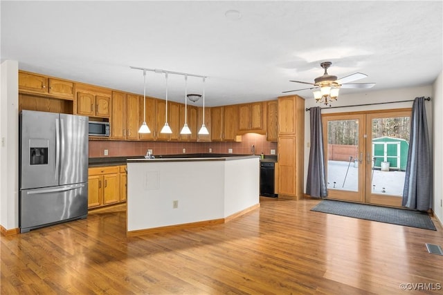 kitchen featuring stainless steel appliances, pendant lighting, backsplash, and light wood-type flooring