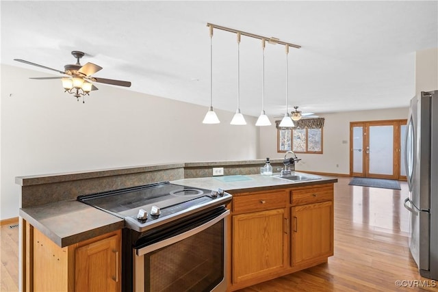 kitchen with sink, decorative light fixtures, light hardwood / wood-style floors, and appliances with stainless steel finishes