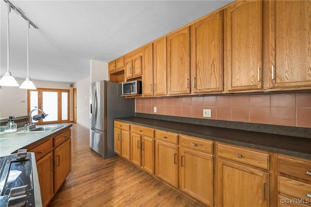 kitchen featuring sink, decorative light fixtures, light wood-type flooring, stainless steel appliances, and decorative backsplash