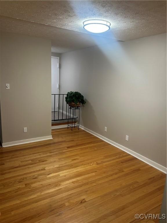 spare room featuring light hardwood / wood-style floors and a textured ceiling