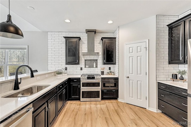 kitchen featuring decorative light fixtures, stainless steel appliances, tasteful backsplash, light hardwood / wood-style floors, and sink