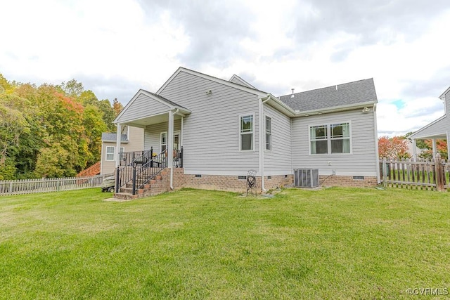 rear view of property featuring central air condition unit and a lawn