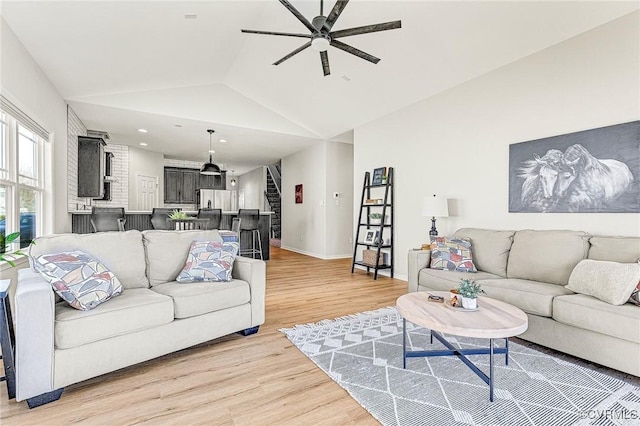 living room featuring hardwood / wood-style flooring, ceiling fan, and vaulted ceiling