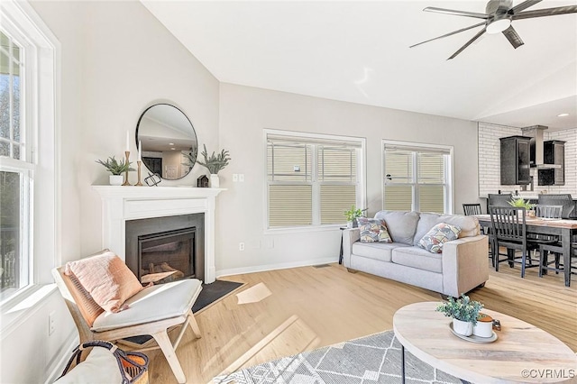 living room with ceiling fan, light wood-type flooring, and vaulted ceiling