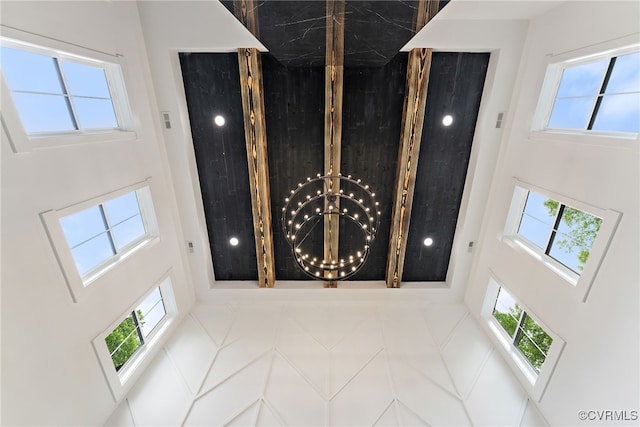 foyer entrance featuring a wealth of natural light, a towering ceiling, and an inviting chandelier