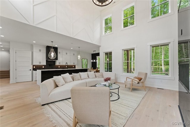 living room featuring recessed lighting, baseboards, a towering ceiling, and light wood finished floors