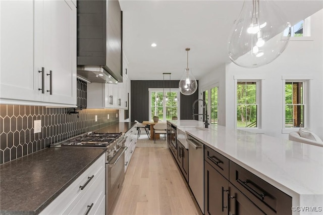 kitchen featuring tasteful backsplash, dark stone countertops, white cabinets, light wood-style floors, and stainless steel appliances