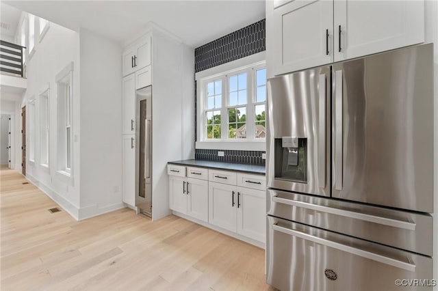 kitchen featuring stainless steel fridge with ice dispenser, visible vents, white cabinets, dark countertops, and light wood finished floors