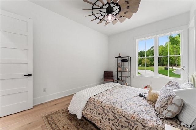 bedroom with baseboards, light wood finished floors, and ceiling fan