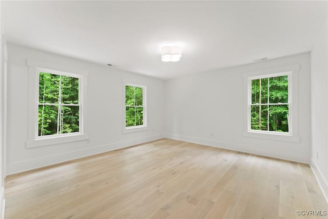 empty room with visible vents, baseboards, and light wood-type flooring