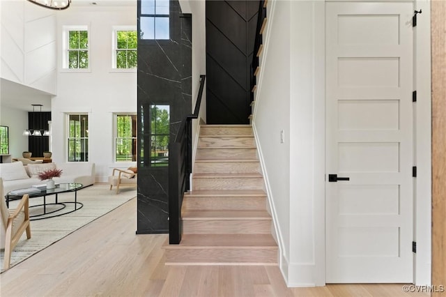 staircase with a barn door, wood finished floors, a towering ceiling, and baseboards