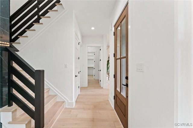 hallway with baseboards, light wood-type flooring, recessed lighting, and stairs