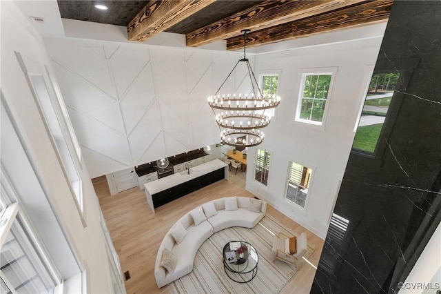 staircase featuring beam ceiling, a chandelier, and wood finished floors