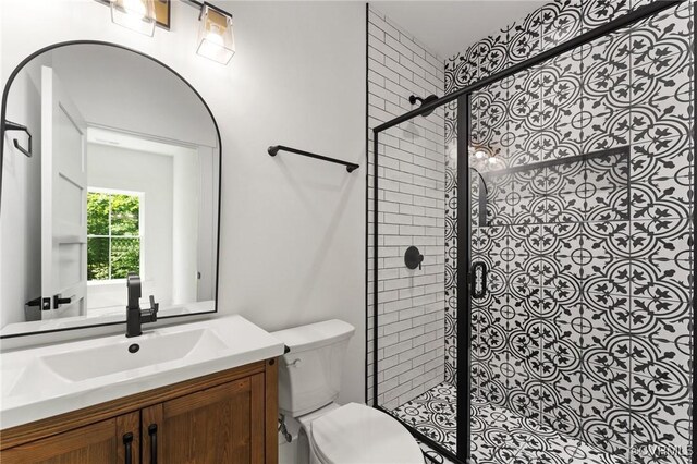 bathroom with toilet, a tile shower, and vanity