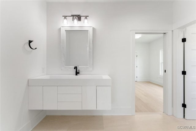bathroom with wood finished floors, vanity, and baseboards
