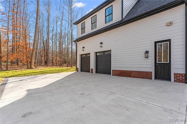 view of property exterior featuring an attached garage, a shingled roof, and driveway