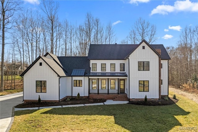 modern farmhouse style home featuring board and batten siding, a front lawn, a shingled roof, and a standing seam roof