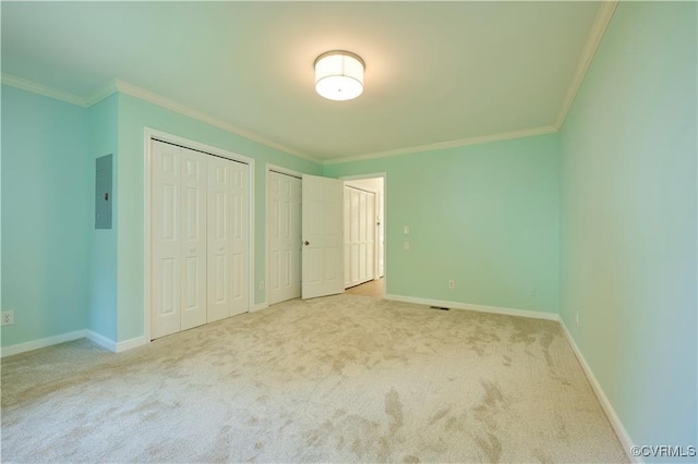 unfurnished bedroom featuring crown molding, carpet, two closets, and electric panel