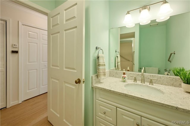 bathroom with vanity, hardwood / wood-style floors, walk in shower, and toilet