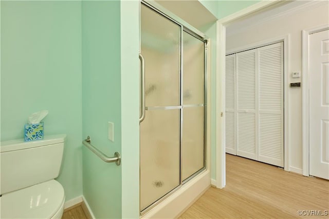 bathroom featuring walk in shower, ornamental molding, toilet, and hardwood / wood-style flooring