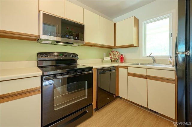 kitchen featuring white cabinetry, sink, black appliances, and light wood-type flooring