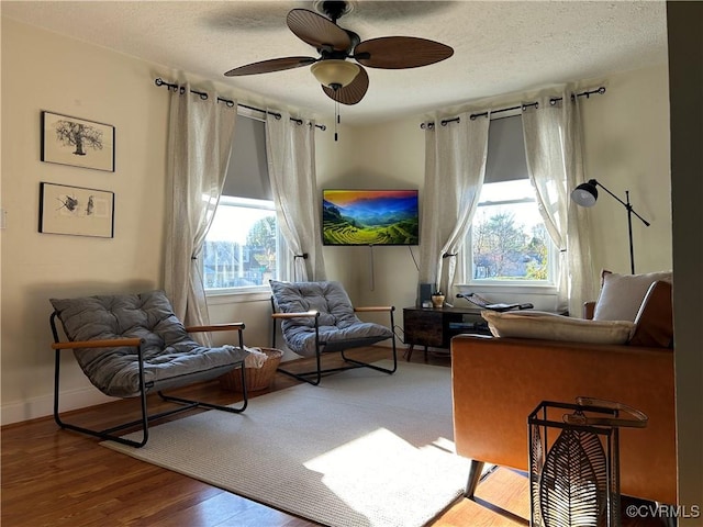 living area featuring hardwood / wood-style flooring, a textured ceiling, and ceiling fan