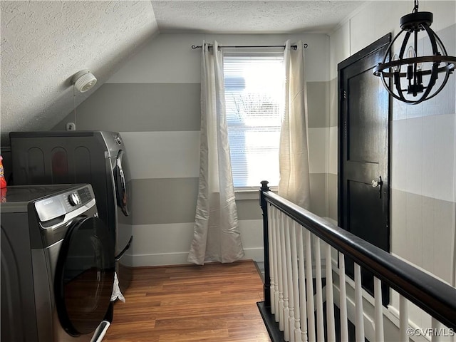 laundry area with a textured ceiling, a wealth of natural light, washing machine and dryer, and wood-type flooring