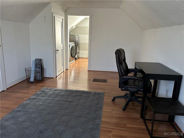 office with vaulted ceiling, a textured ceiling, washer and clothes dryer, and wood-type flooring