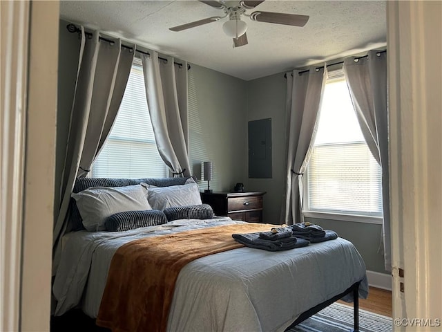 bedroom featuring ceiling fan, hardwood / wood-style floors, and electric panel