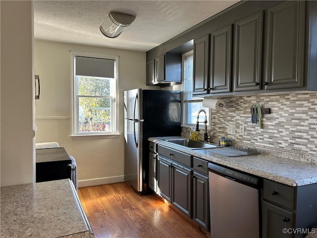 kitchen with a textured ceiling, wood-type flooring, stainless steel appliances, sink, and gray cabinets