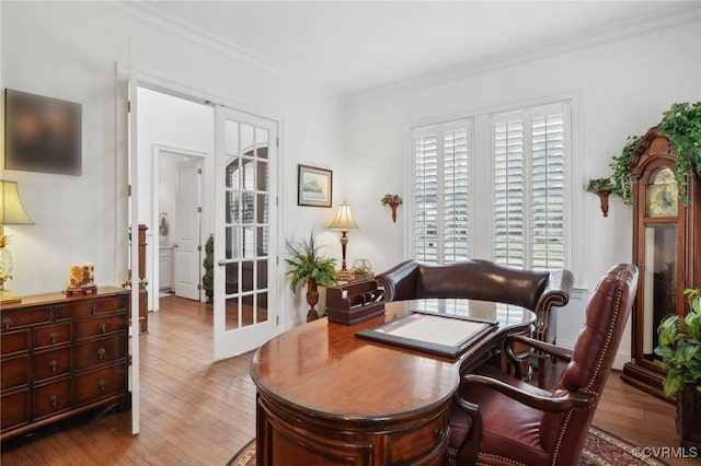 home office with light hardwood / wood-style floors, ornamental molding, and french doors